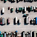 Aerial view of parking lot filled with trucks, buses, and a car
